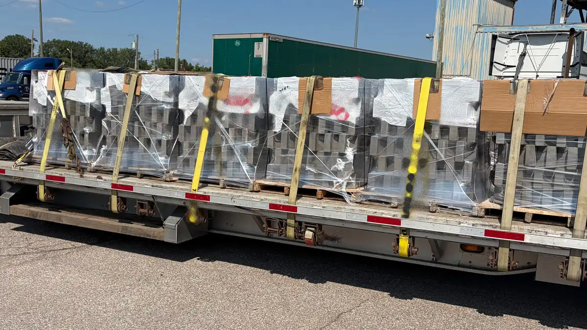 The same flatbed load rebuilt square and level, blocked with lumber dunnage and evenly strapped