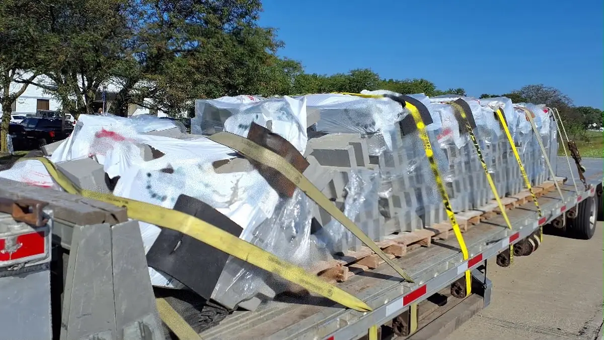 Flatbed trailer carrying palletized masonry product with the stacks leaning and shifted out of position